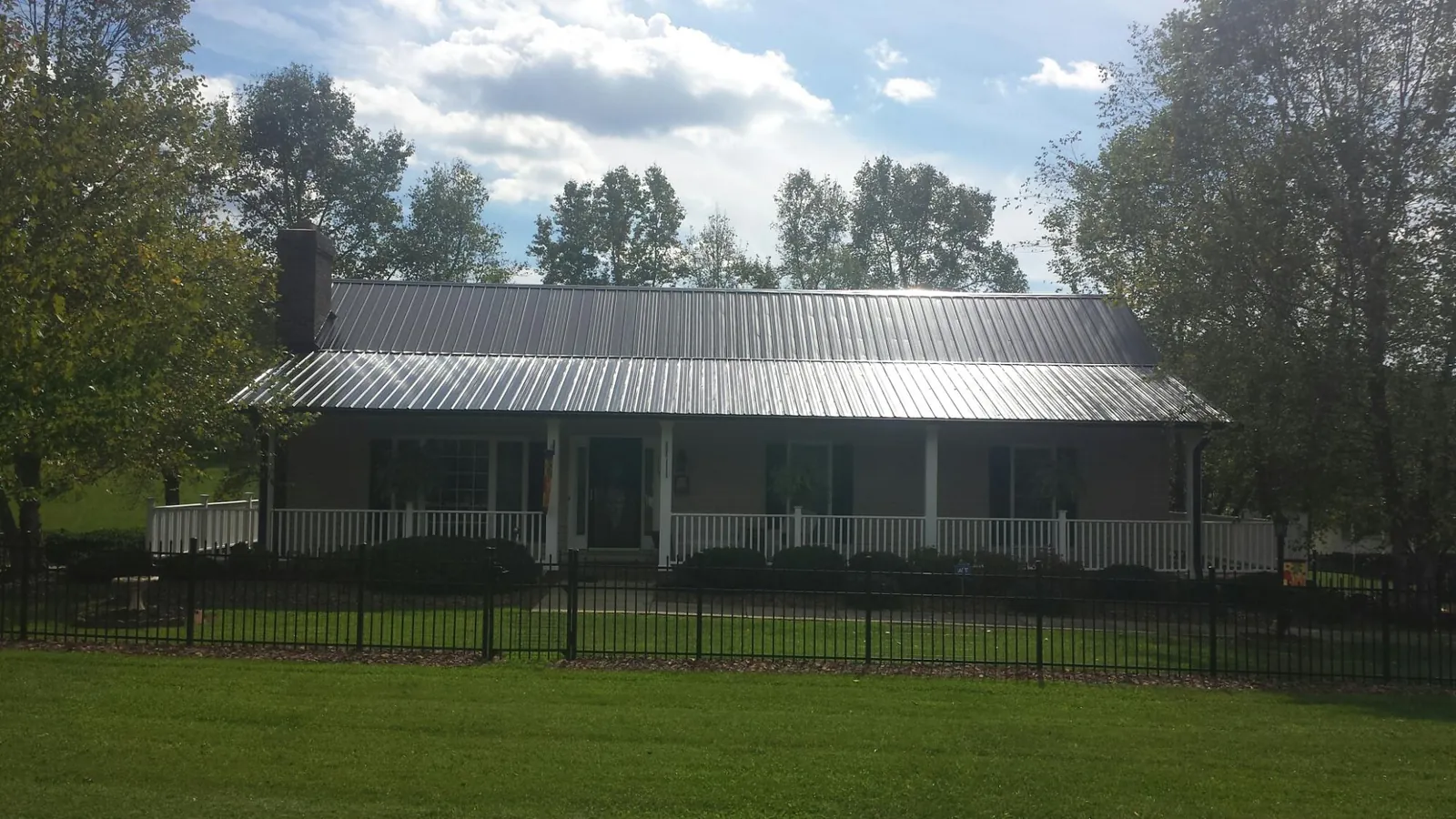 Gray metal roof on a brick ranch with a full width front porch — Gutter Guard Installation work by our crew in Dillsboro