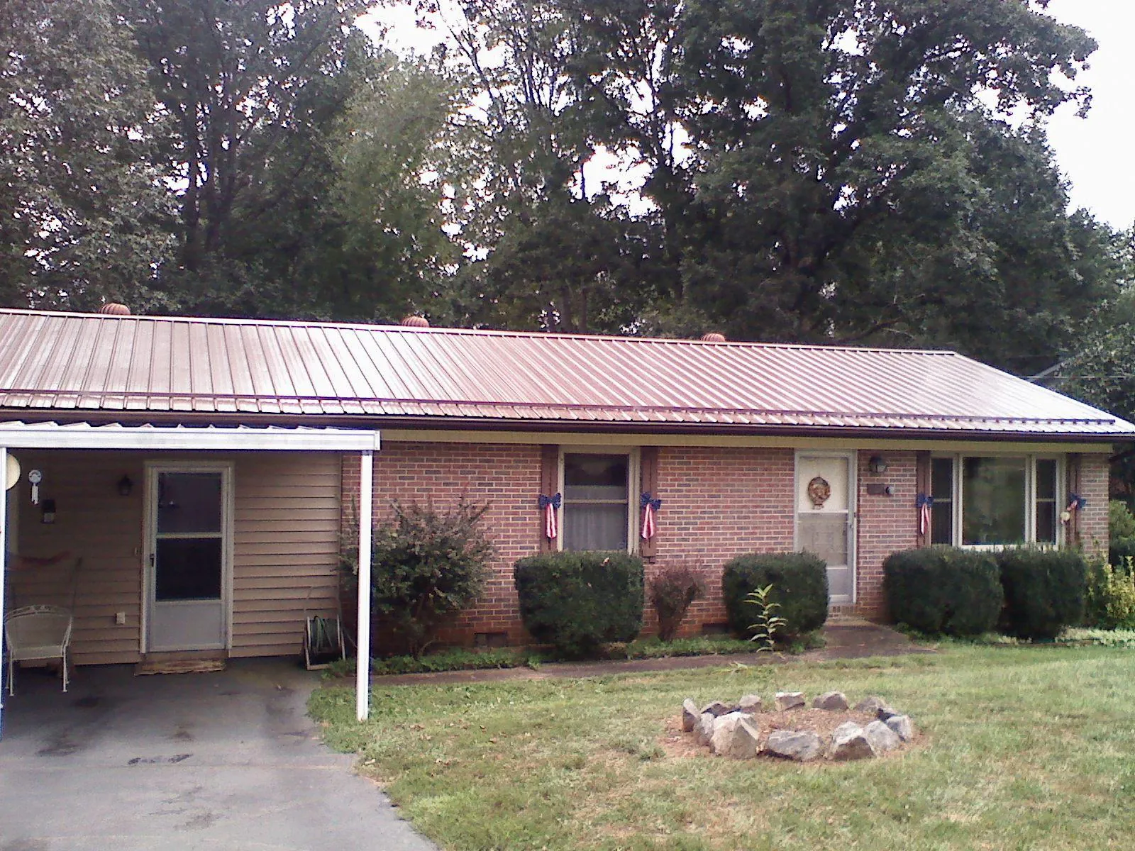 Bronze metal roof and carport on a brick ranch home — Roof Repair work by our crew in Dillsboro