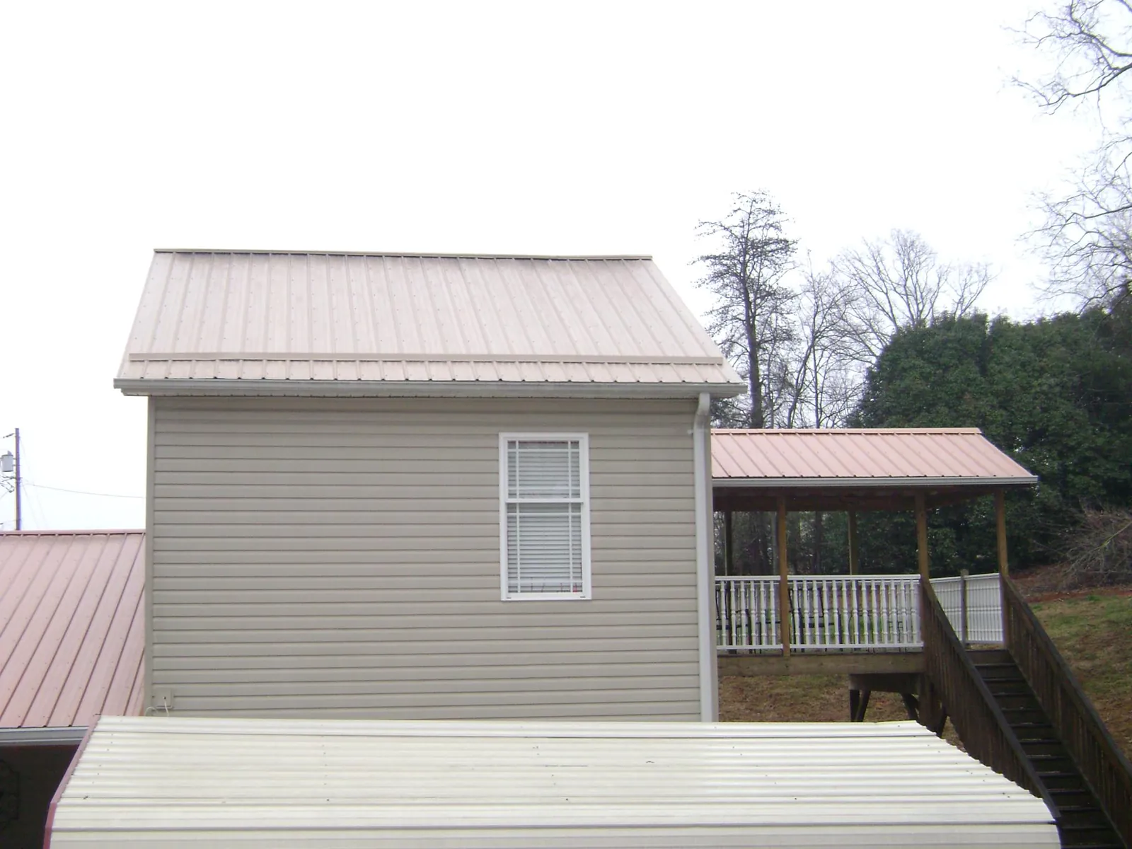 Tan metal roofs on a two story addition and attached porch, from a Roof Replacement job in Dillsboro